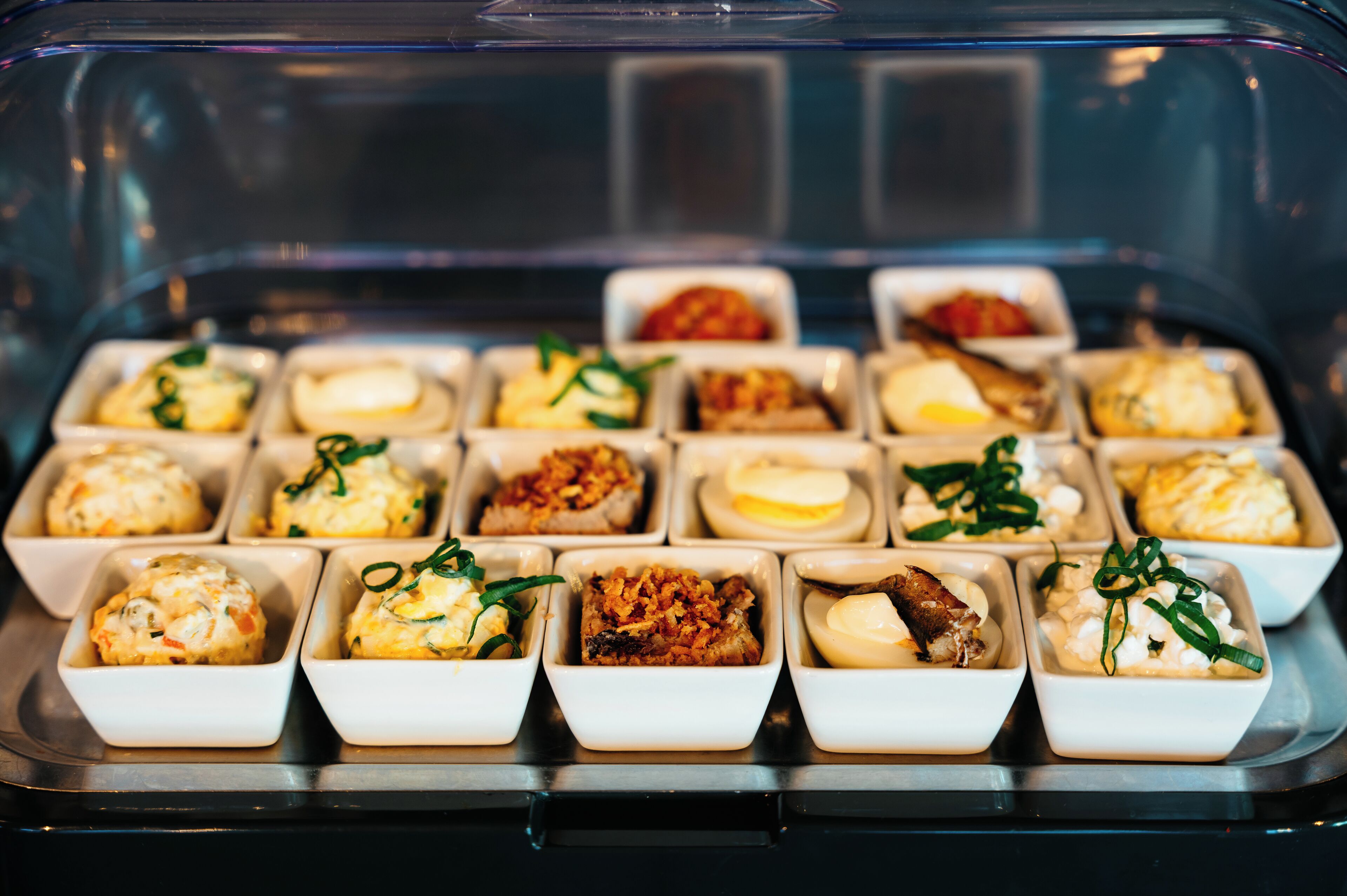 A variety of small dishes arranged in a clear container, likely for serving as appetizers or snacks.