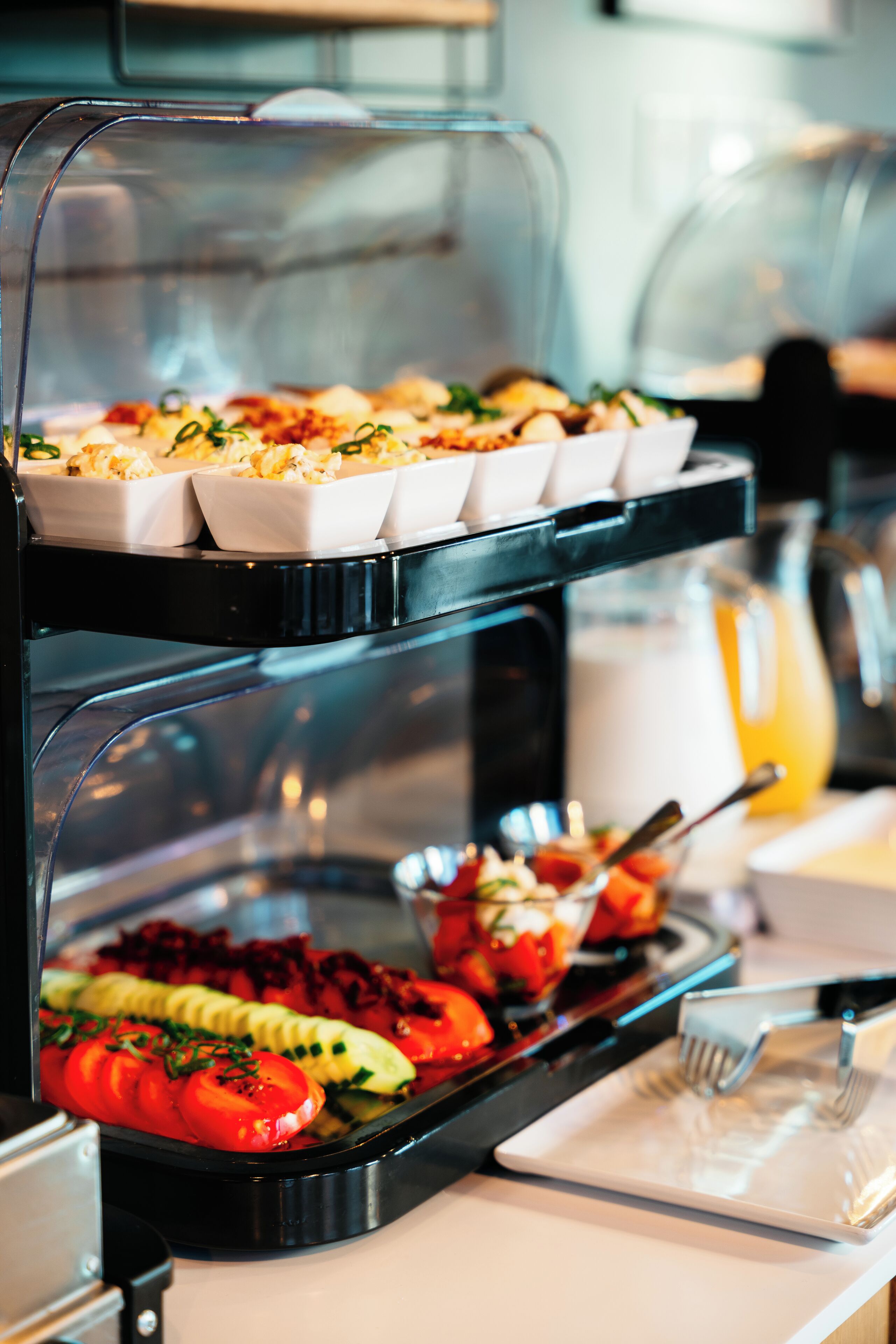 A buffet with various food items including sliced tomatoes, cucumbers, and a salad.