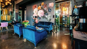 A modern interior with a blue sofa set, a coffee machine, and a bookshelf filled with books. - Amber Suite Szczecin Adults Only (Szczecin)
