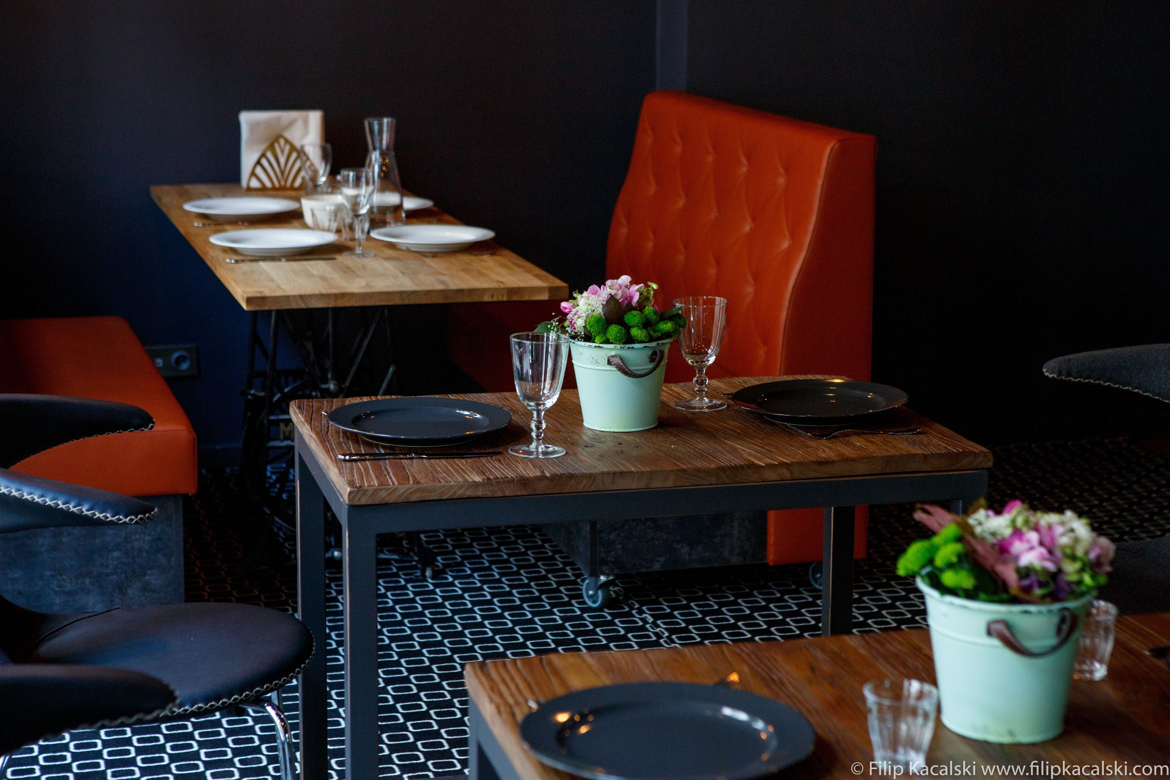 Een eetgedeelte met een houten tafel gedekt voor twee personen, een rode fauteuil en een vloer met een patroon.