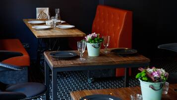 Un comedor con una mesa de madera dispuesta para dos personas, una silla tapizada de rojo y un suelo estampado.