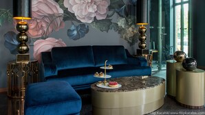 A modern living room with a blue sofa, a round coffee table, and a floral mural on the wall. - Amber Suite Szczecin Adults Only (Szczecin)