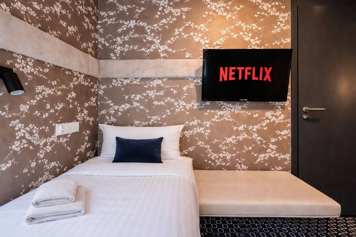 Ein Hotelzimmer mit einem Bett, einem an der Wand befestigten Fernseher und einer Tür.