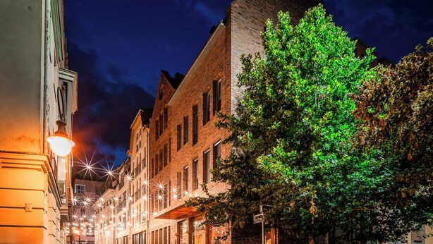 A nighttime street scene with buildings, a tree, and street lamps. - Amber Suite Szczecin Adults Only (Szczecin)