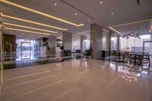 A modern hotel lobby with a polished floor, contemporary furniture, and decorative lighting.
