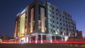Un hotel moderno con una entrada destacada, amplias ventanas y un diseño de fachada distintivo.