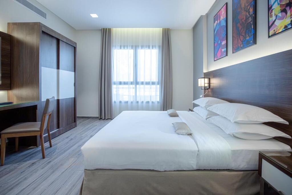 Ein Hotelzimmer mit einem großen Bett, einem Schreibtisch, einem Stuhl und einem Kleiderschrank.