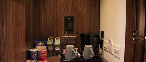 Minibar en una habitación de hotel con aperitivos, una cafetera y un hervidor de agua.