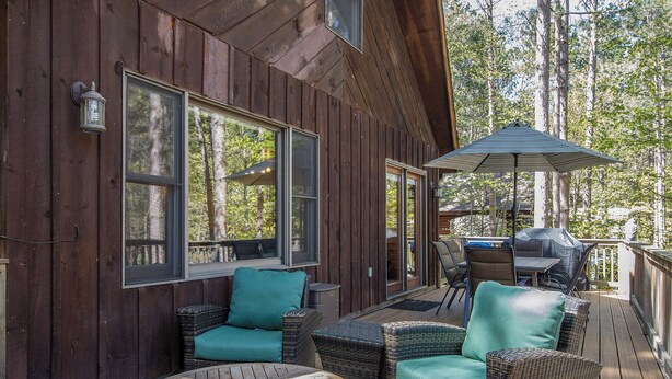 A wooden deck with wicker furniture, large windows, and an umbrella.