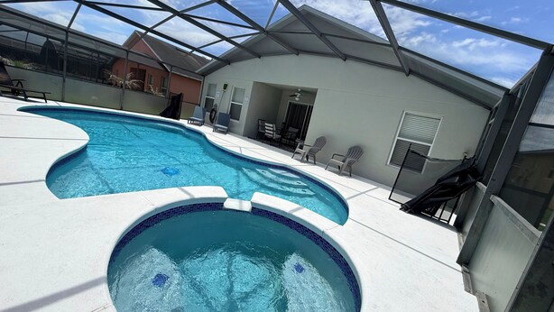 A swimming pool with a glass ceiling, lounge chairs, and a covered patio area. - Free pool heat June, July, August Keyvilla-The Disney Retreat, 5 bed pool home.  (davenport)