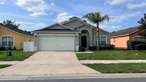 A residential house with a garage, a driveway, and a well-maintained lawn. - Free pool heat June, July, August Keyvilla-The Disney Retreat, 5 bed pool home.  (davenport)