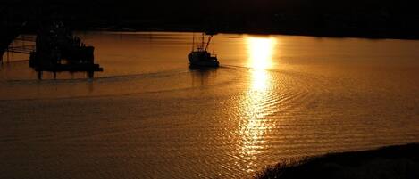 A sunset over a calm body of water with two boats.