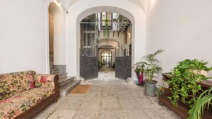 Un hall d’entrée spacieux, agrémenté d’un canapé à motifs floraux, de plantes en pot et d’un escalier menant à l’étage supérieur.