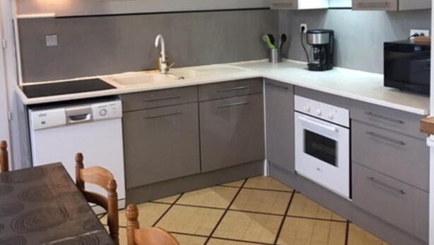 Una cocina compacta equipada con lavavajillas, estufa, microondas y un comedor con mesa y sillas.