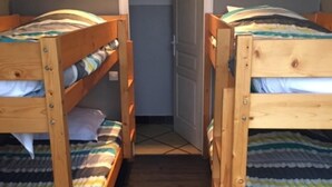 Una habitación con dos literas, una puerta y una pequeña lámpara fijada a la pared.