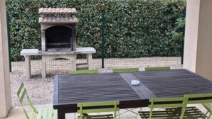 Un patio al aire libre con mesa y sillas, una parrilla y una chimenea de piedra.