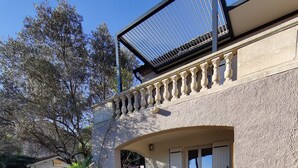 A building with a stone exterior, a covered patio area, and a view of the surrounding landscape. - Independent apartment in Languedoc villa with panoramic views (Combaillaux)