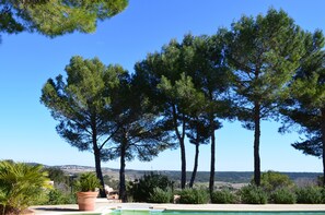 A pool area with tall trees and a clear view of the landscape. - Independent apartment in Languedoc villa with panoramic views (Combaillaux)