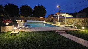 Patio trasero con piscina, sillas de descanso y un área de terraza cubierta.