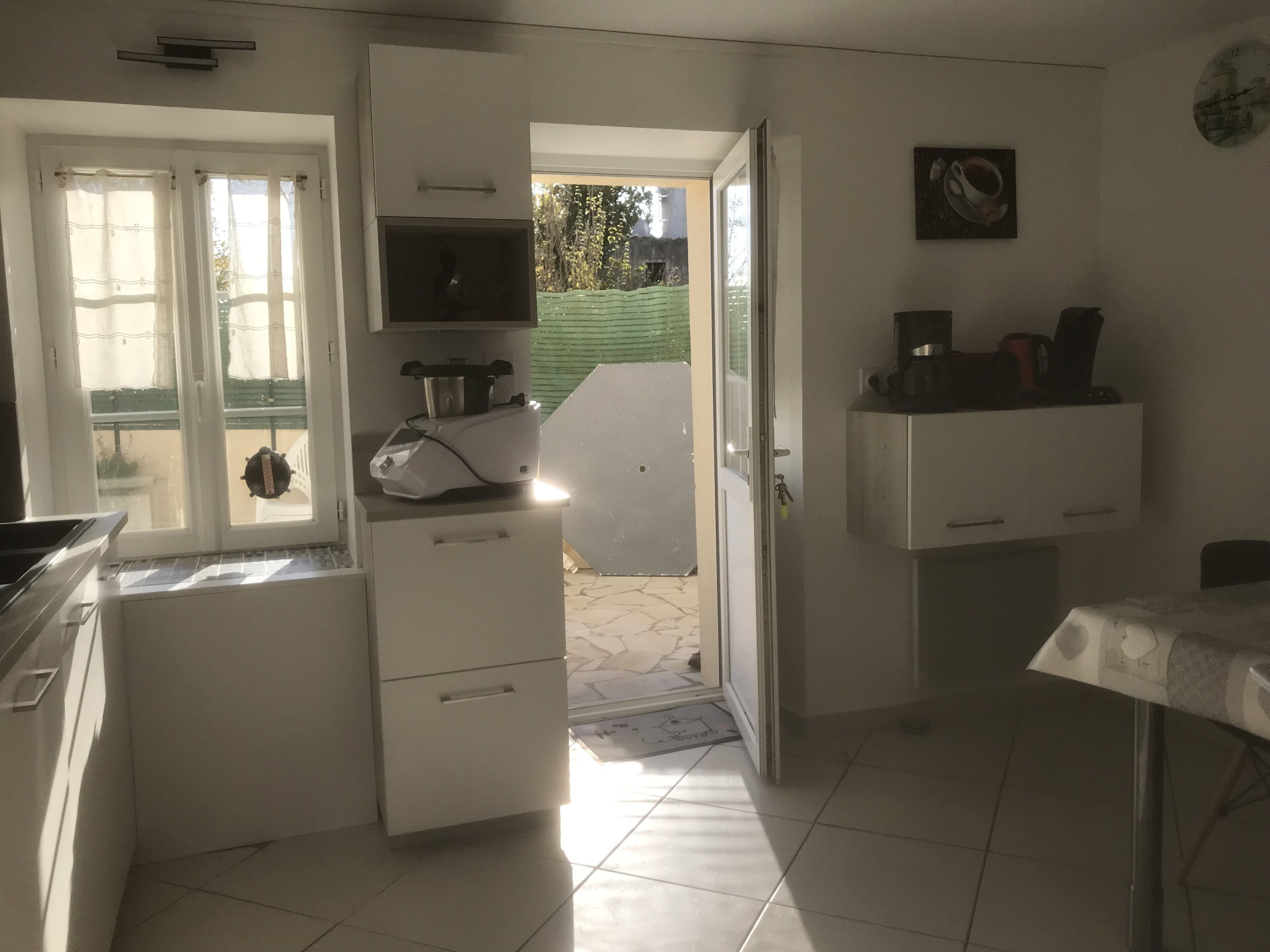 Eine kompakte Küche mit weißen Schränken, einem eingebauten Backofen und einer Kaffeemaschine.