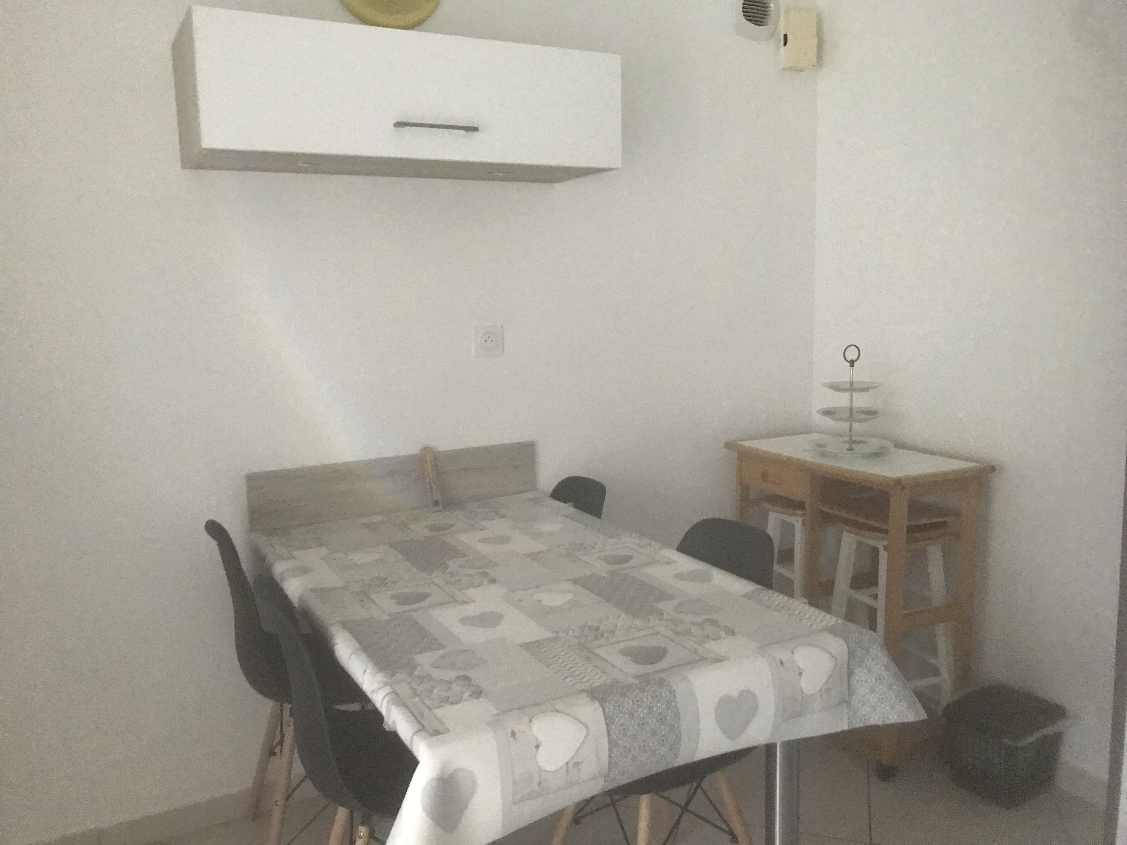 Un espace repas avec une table recouverte d’une nappe à motifs, entourée de chaises.