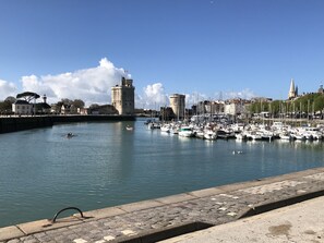 A marina with boats docked, a castle, and a lighthouse.