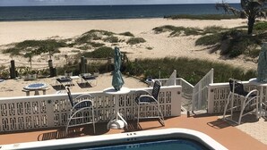 Een zwembadgedeelte met ligbedden en uitzicht op het strand.