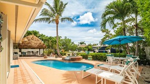 A pool area with lounge chairs, a hot tub, and palm trees. - P13 - Loggerhead House 3 Bedroom Home with Private Pool (Key Colony Beach)