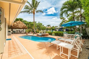 Un espace piscine avec des chaises longues, un jacuzzi et des palmiers.