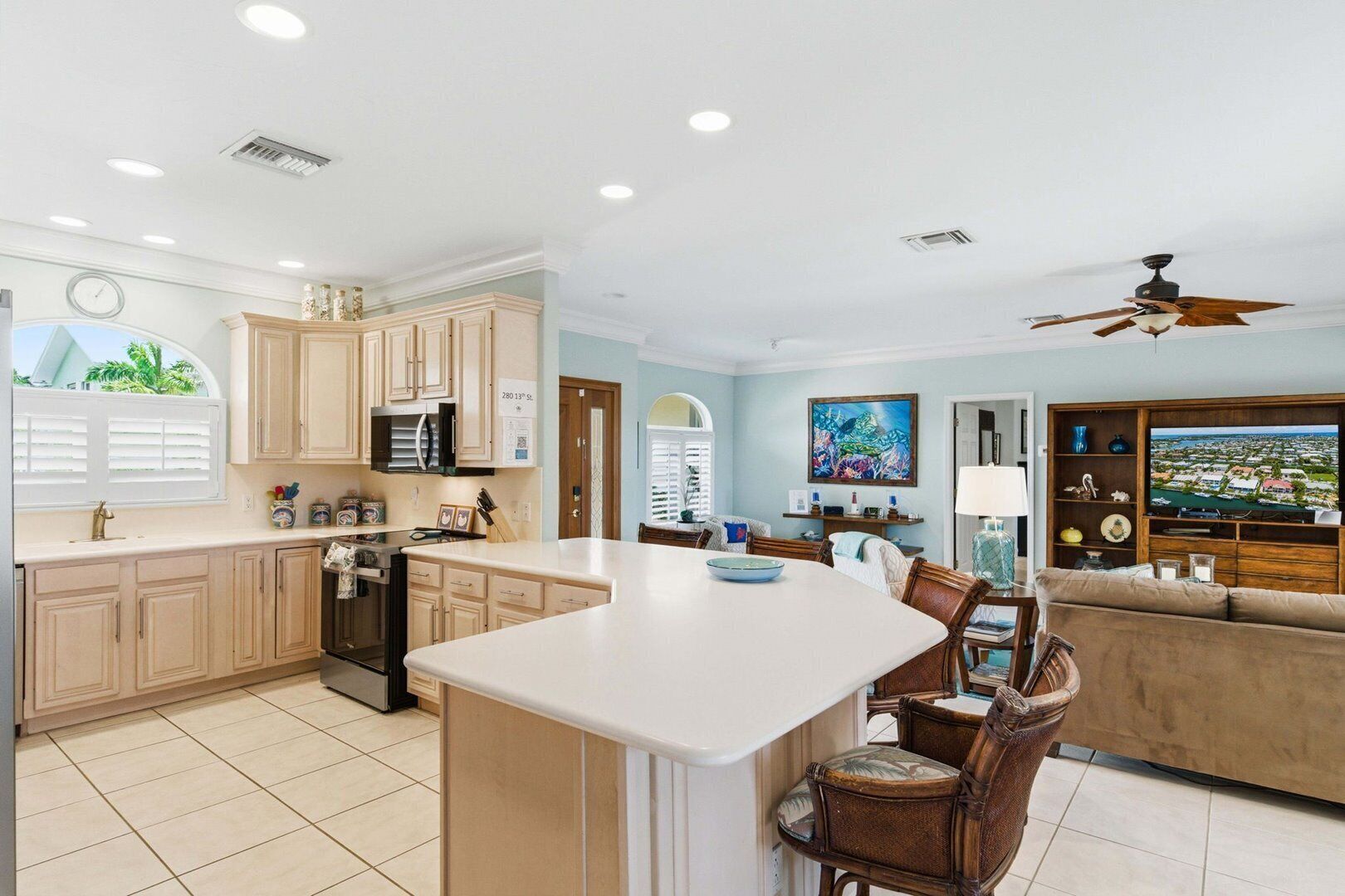 A spacious kitchen with a central island, dining area with chairs, a sofa, and a TV.