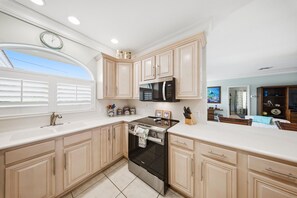 A kitchen with light-colored cabinets, a stainless steel stove, and a microwave. - P13 - Loggerhead House 3 Bedroom Home with Private Pool (Key Colony Beach)