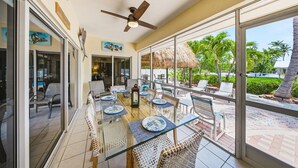 A sunlit patio with a glass table, wicker chairs, and a ceiling fan. - P13 - Loggerhead House 3 Bedroom Home with Private Pool (Key Colony Beach)