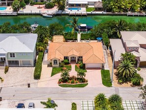 A residential property with a swimming pool, a boat docked by the water, and a well-maintained garden. - P13 - Loggerhead House 3 Bedroom Home with Private Pool (Key Colony Beach)