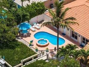 A rooftop swimming pool with lounge chairs and a hot tub, surrounded by palm trees and greenery. - P13 - Loggerhead House 3 Bedroom Home with Private Pool (Key Colony Beach)