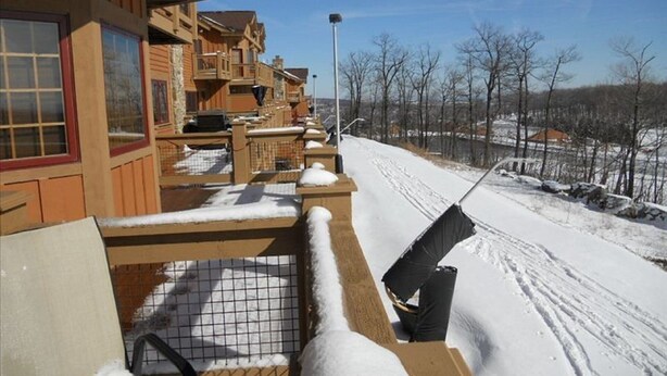Eine Holzdiele mit verschneietem Deck und Blick auf eine verschneite Landschaft.