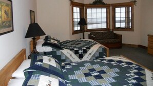 Ein Zimmer mit einem Bett, einem Sessel, einer Lampe und einem Fenster mit Jalousien.