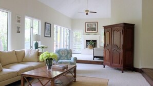 A living room with a sofa, armchair, coffee table, and a wooden cabinet. - Charming, family friendly and updated kitchen (Kiawah Island)