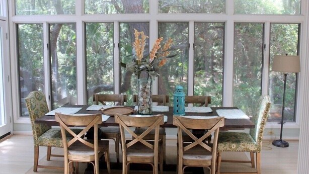 A dining area with a large window, wooden chairs, a table, and a vase with flowers. - Charming, family friendly and updated kitchen (Kiawah Island)