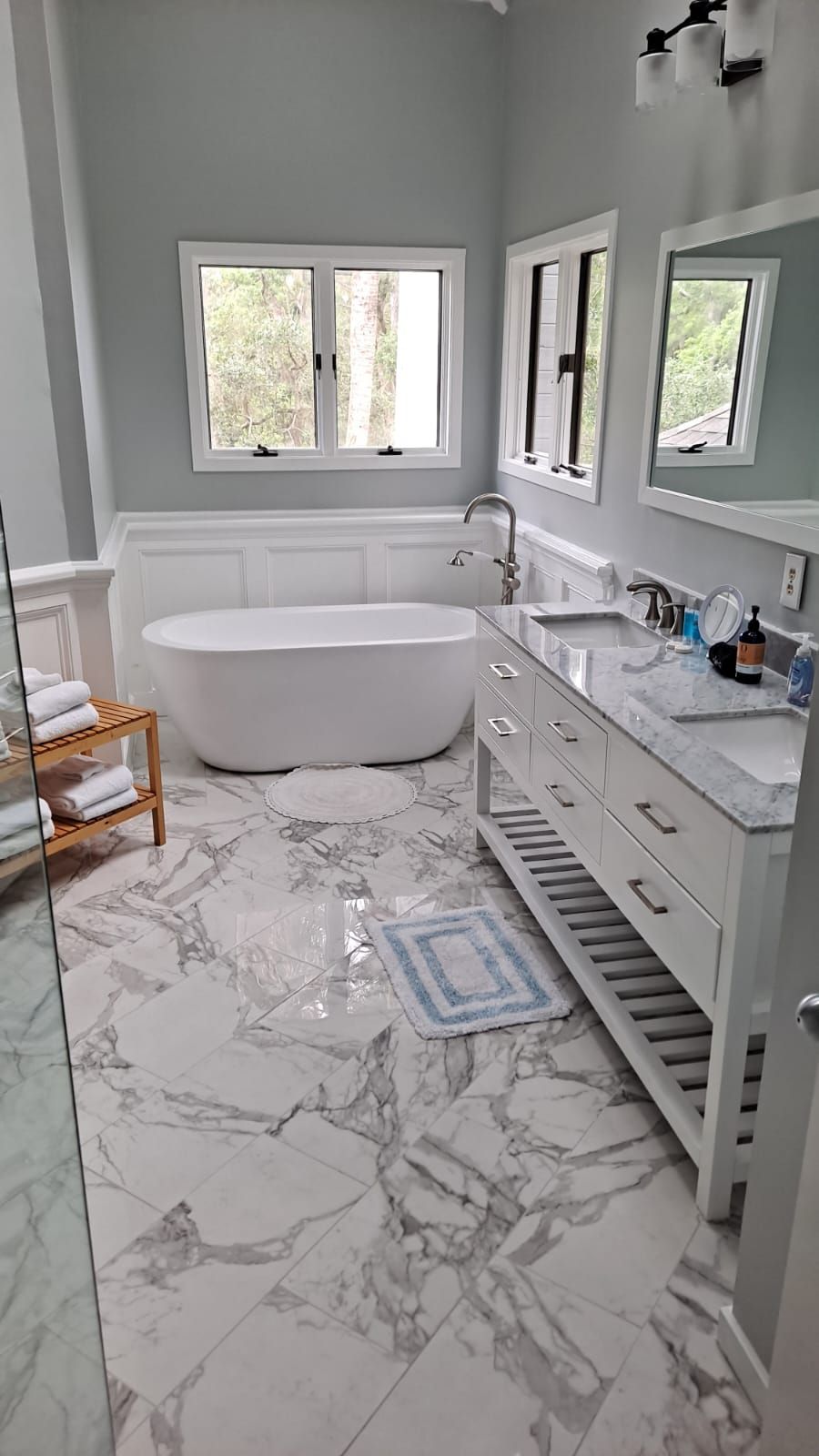 A bathroom with a freestanding bathtub, a vanity with a sink, and a mirror above the vanity.