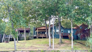A lakeside property with a house, a dock, and a small docked boat. - Family house by the lake (Shelby)