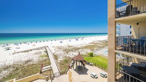 Vue sur la plage depuis un balcon agrémenté d’un belvédère, d’une piscine et d’un espace salon extérieur.