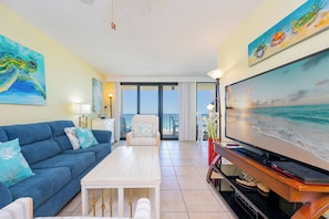 A living room with a sofa, coffee table, TV, and artwork. - Everything is Better at the Beach! ~ Popular One Bedroom @ Phoenix 1 (Orange Beach)