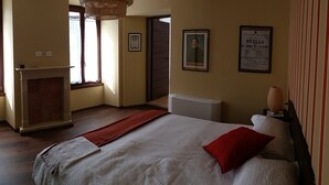 A hotel room with a bed, a fireplace, a window, and a wall with a framed picture and a poster. - Carlito's trattoria con alloggio (Cucciago)