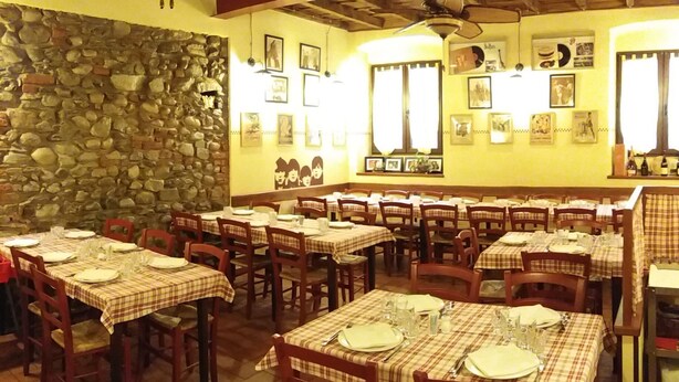 A restaurant with multiple tables set for dining, stone walls, and ceiling fans. - Carlito's trattoria con alloggio (Cucciago)