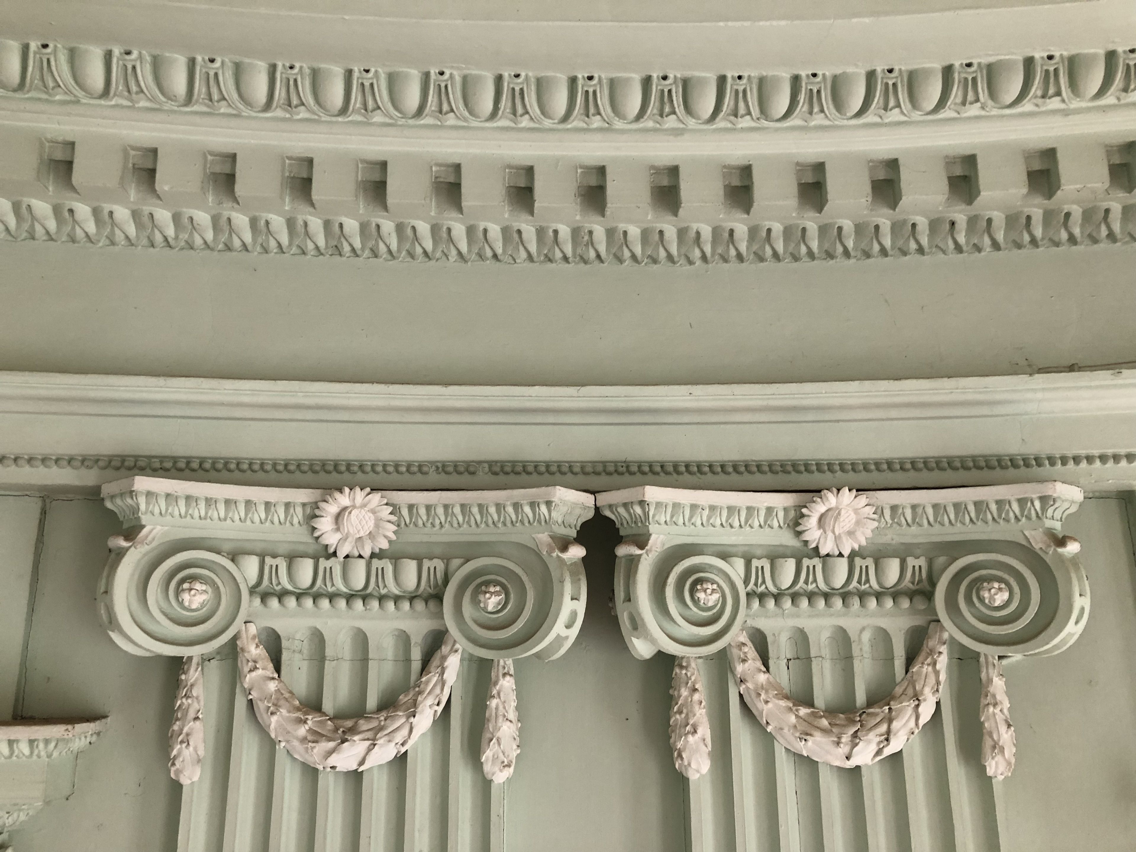 Un detallado techo arquitectónico con columnas clásicas y adornos decorativos.
