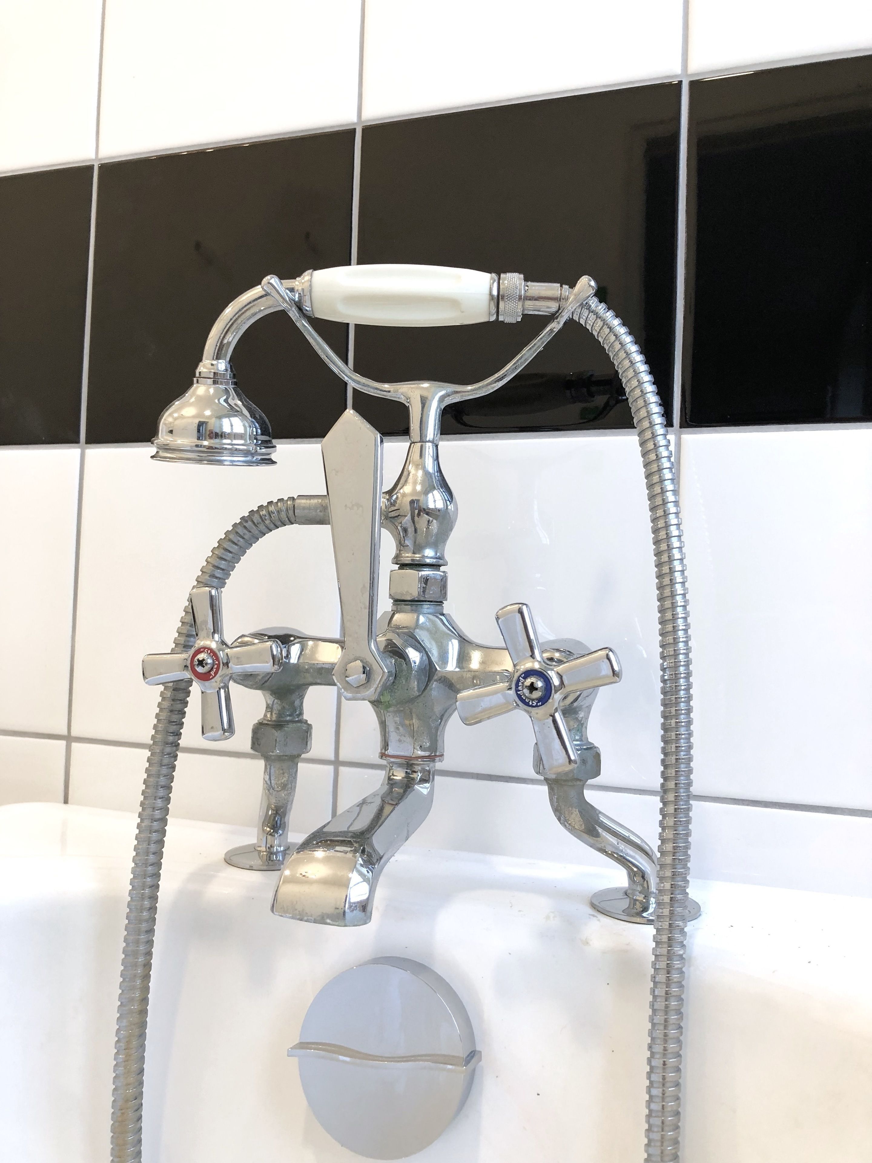 Une salle de bain équipée d’un pommeau de douche chromé, d’un pommeau de douche à main et d’un tuyau flexible.