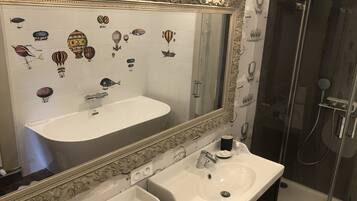 Une salle de bain avec un grand miroir, deux lavabos et une douche.