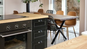 Una cocina moderna con encimera de madera, horno integrado y comedor con sillas y una mesa.