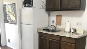 Une cuisine avec un réfrigérateur blanc, des placards en bois, un plan de travail en granit et un panneau indiquant où se trouve le livre d’or.