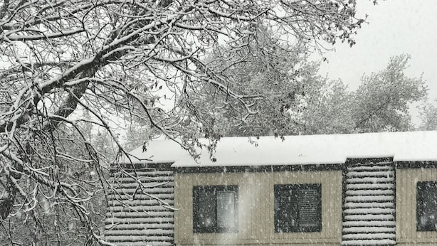 Une maison avec un toit en pente et une porte de garage. De fortes chutes de neige recouvrent les environs de la maison.